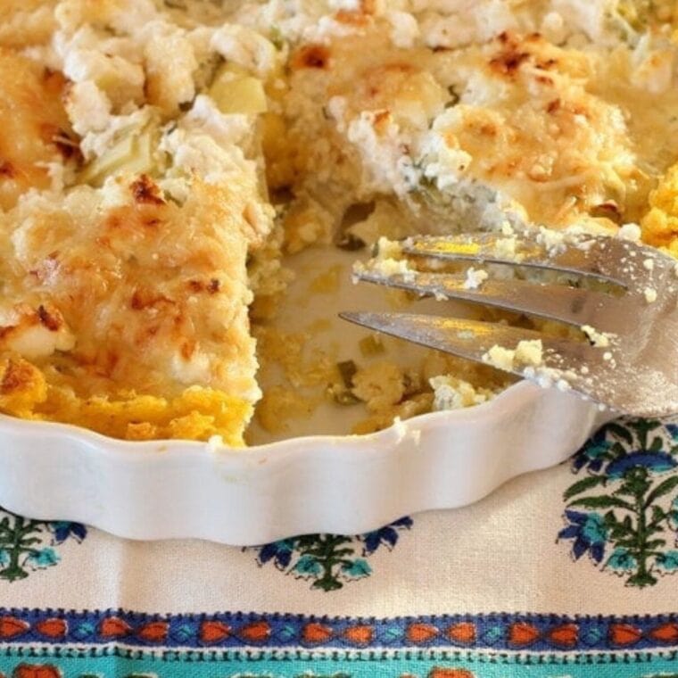 Close up photo of an artichoke tart with polenta crust in a white tart pan.