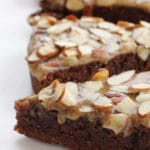 3 slices of gluten-free chocolate cake topped with brown sugar icing and almonds.