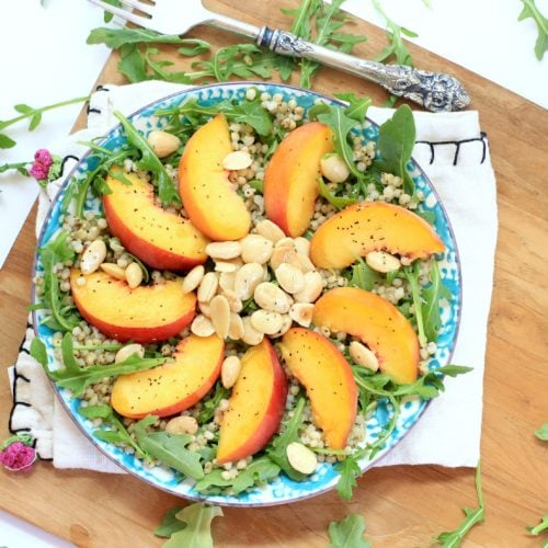 Arugula Salad with Peaches and almonds on a blue and white plate