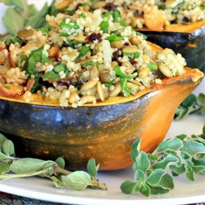 vegetarian stuffed acorn squash with fresh oregano on a white platter