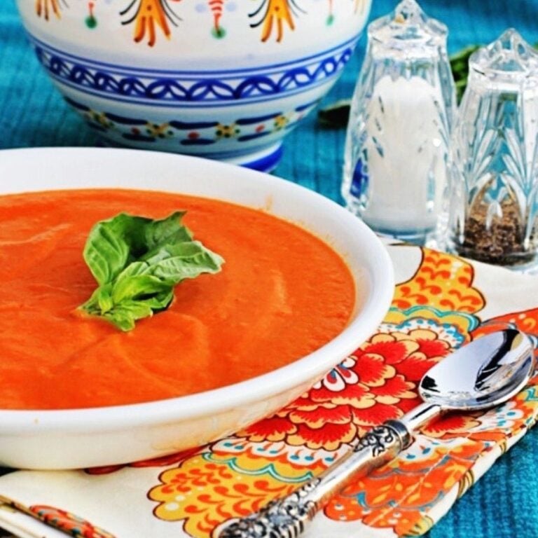 Cream of tomato soup in a white bowl with a colorful napkin in the background.