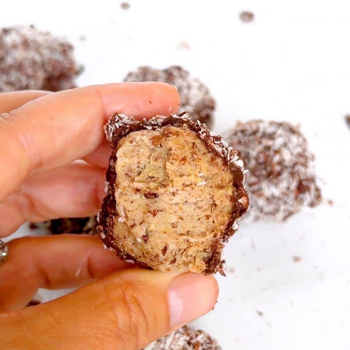 Close up shot of a hand holding a half eaten chocolate energy ball.