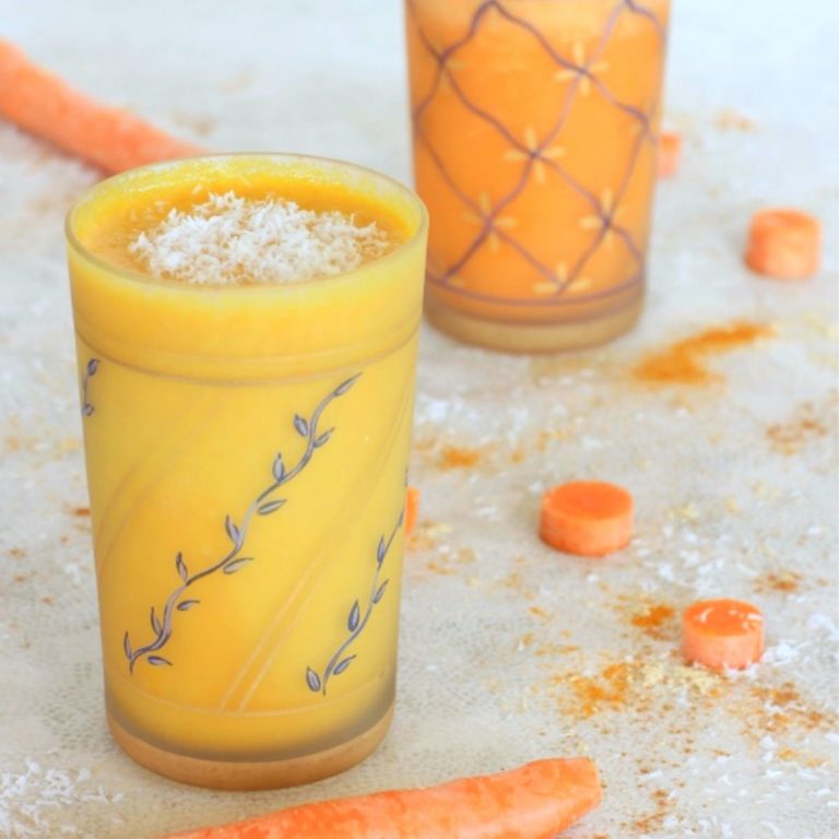 carrot cake smoothie in a glass with carrots and spices on a white background
