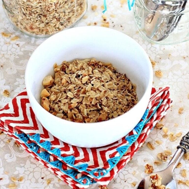 Low FODMAP granola in a white bowl on a red and white chevron striped napkin.
