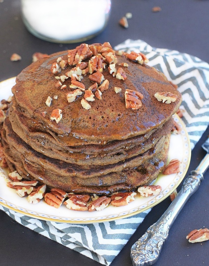Gluten Free Gingerbread Pancakes on a plate topped with pecans and maple syrup.