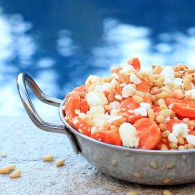 Steamed carrots with feta and pine nuts in a serving dish.