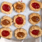 Gluten-free thumbprint cookies on white parchment paper.