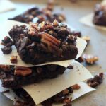A stack of 3 vegan black bean brownies topped with pecans.