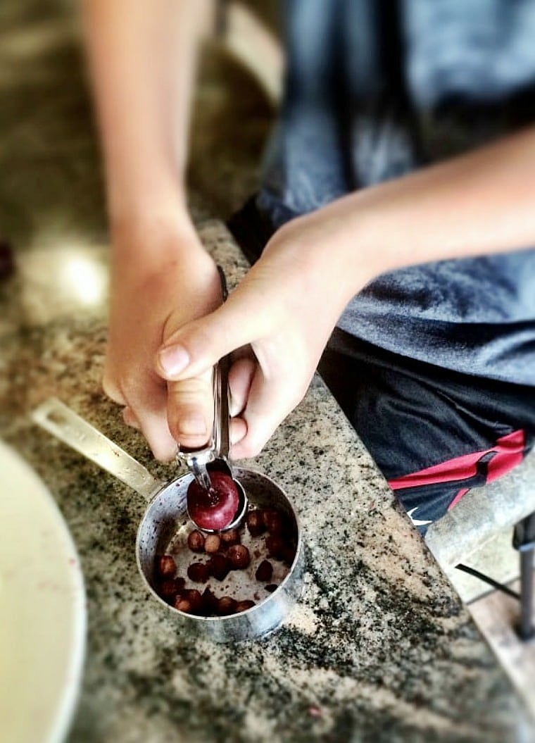 hands holding a cherry pitter