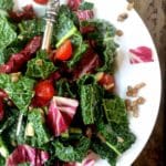 Close up photo of a kale, lentil, tomato, radicchio salad in a white bowl.