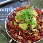 Turkey chili topped with avocado and cilantro in a silver bowl.