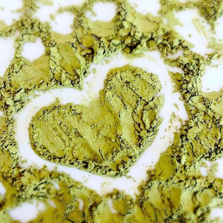 matcha powder in the shape of a heart on a white cutting board.