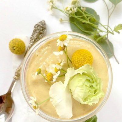 ginger peach mango lassi in a glass topped with fresh flowers
