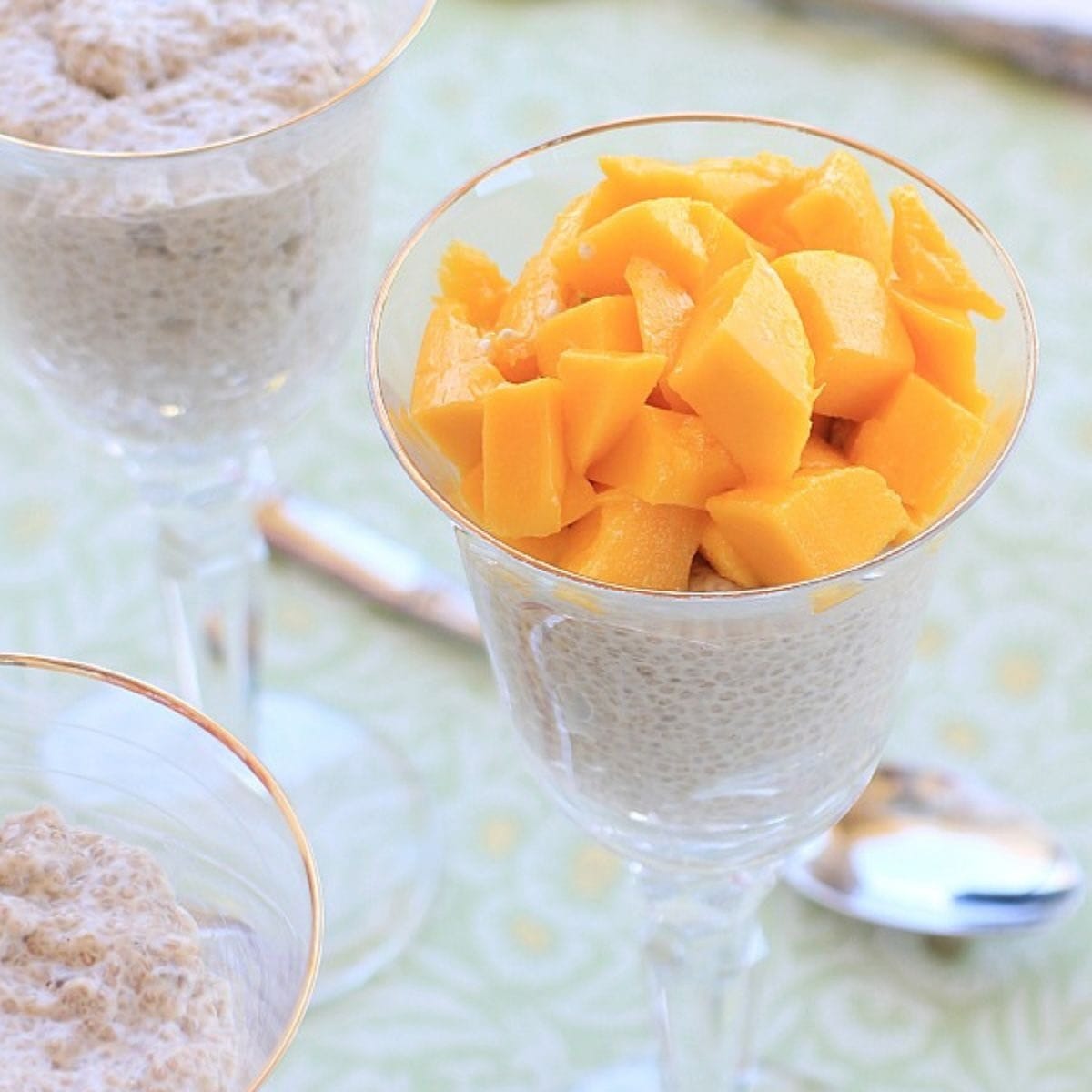 Crystal wine glass filled with chia pudding topped with mango chunks.
