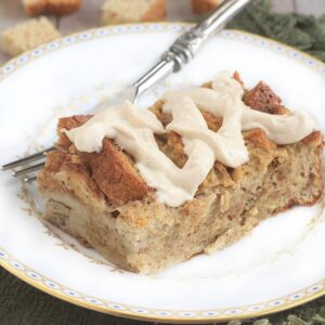 Gluten Free Baked French Toast with Cream Cheese Frosting on a white plate with a silver fork in the background.