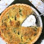 Overhead photo of a gluten free quiche recipes on white marble with 1 slice eaten.