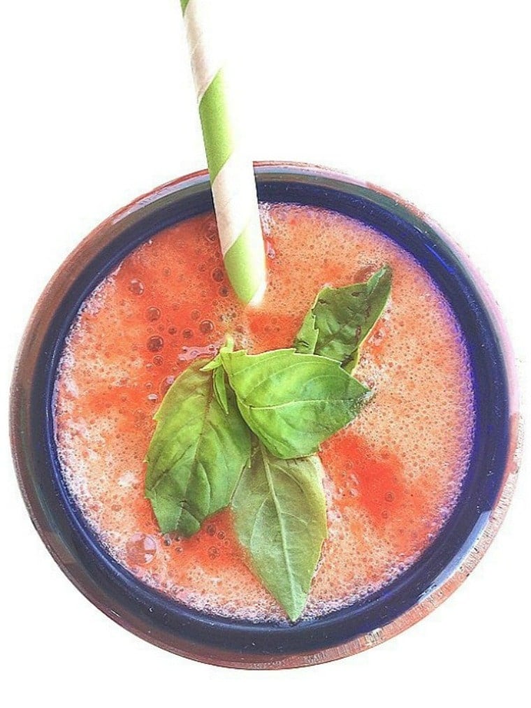 strawberry basil lemonade in a blue rimmed glass with a straw