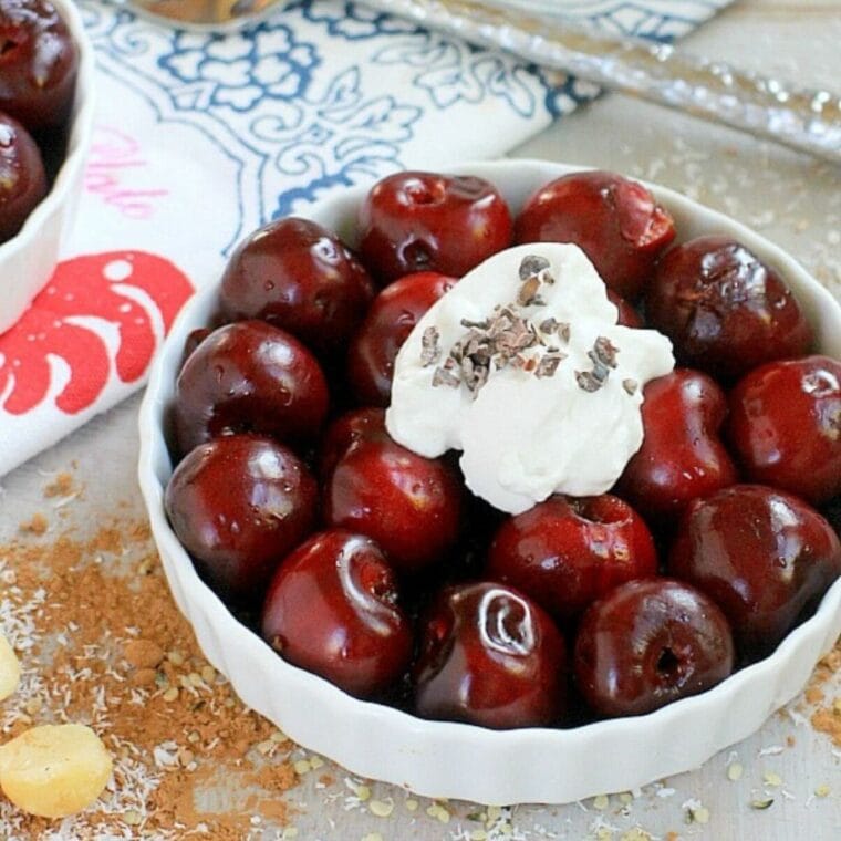 No bake fresh vegan cherry pie in a white dish with coconut whipped cream on top.