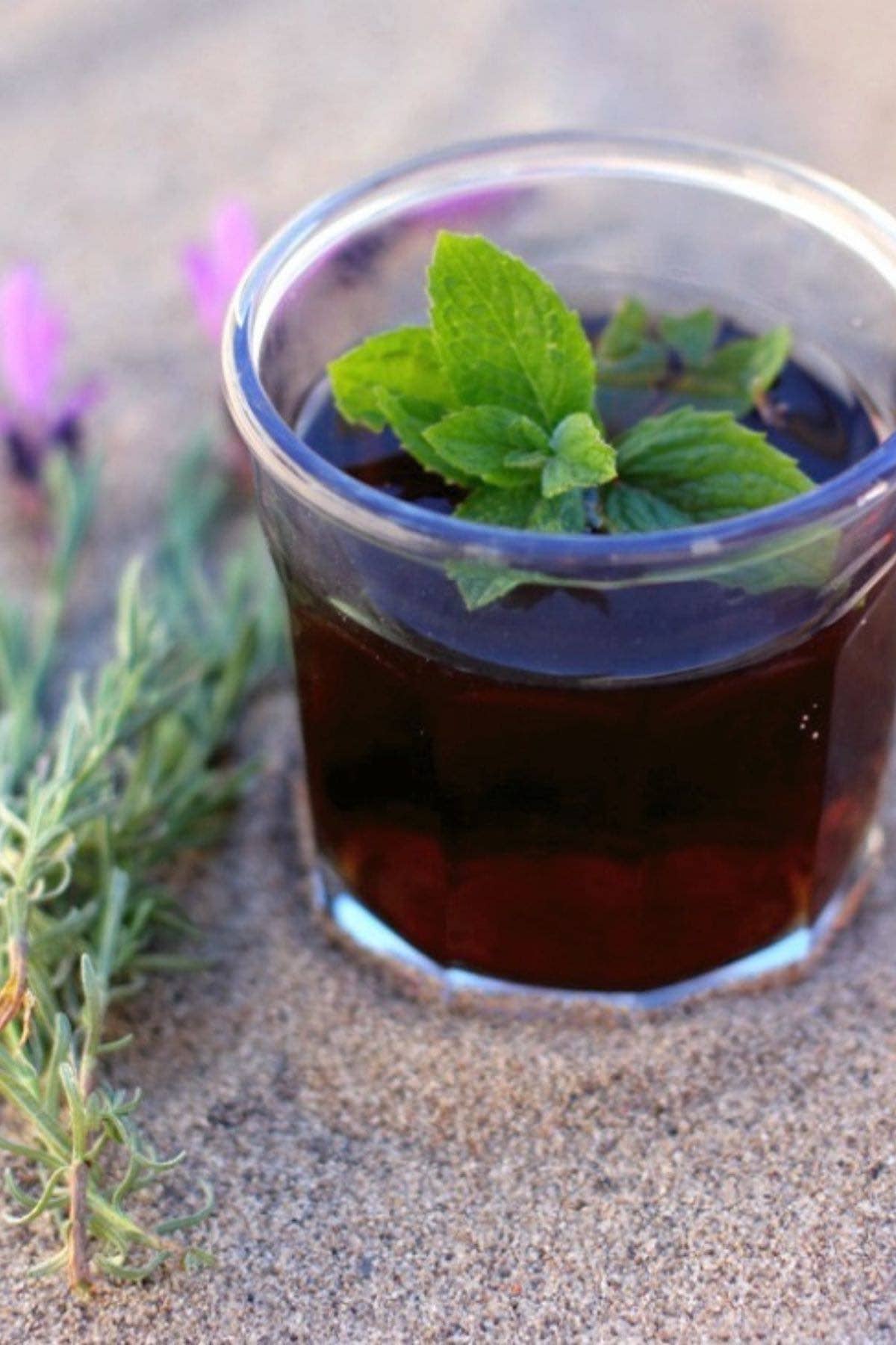 Glass of lavender iced tea topped with mint.
