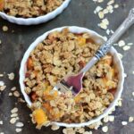 Gluten-free peach crisp in a white bowl with a fork.