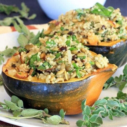 Acorn vegetarian stuffed squash filled with quinoa pilaf on a white dish.