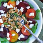 white bowl with toasted beet salad topped with walnuts and greens.