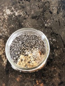Chia seeds and other ingredients in a mason jar to make coconut chia pudding.