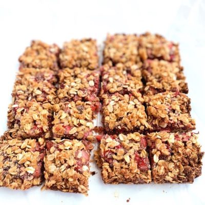 Strawberry Oatmeal Bars cut into squares on white parchment paper