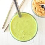 Overhead shot of a bright green flaxseed smoothie with a silver strawon a white background