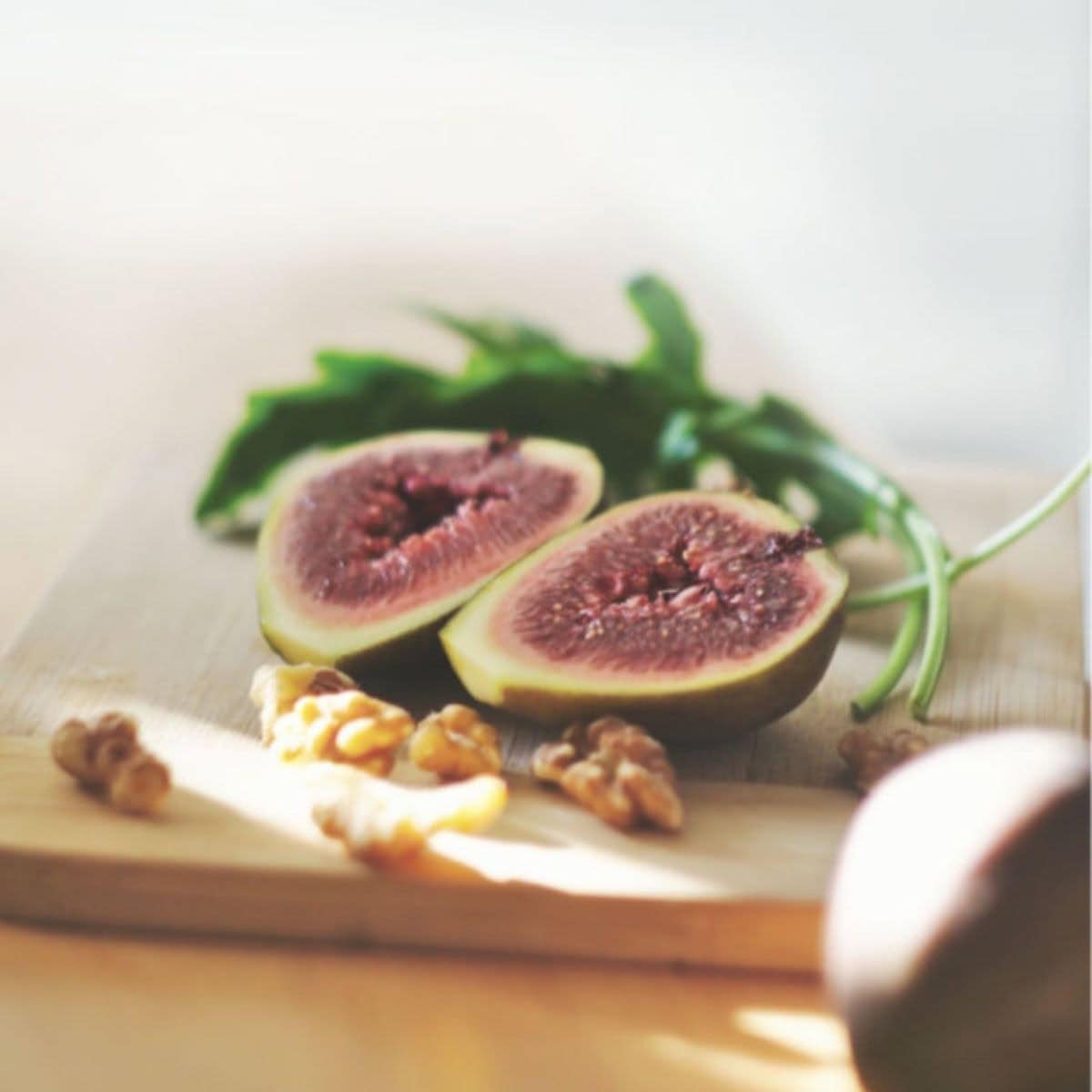 Black fresh figs on a wooden tray with walnuts.