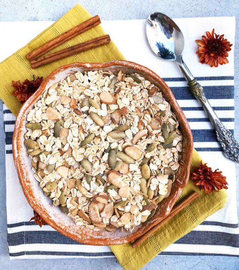 Overhead photo of gluten-free muesli in a terracotta bowl with almonds and pumpkin seeds.