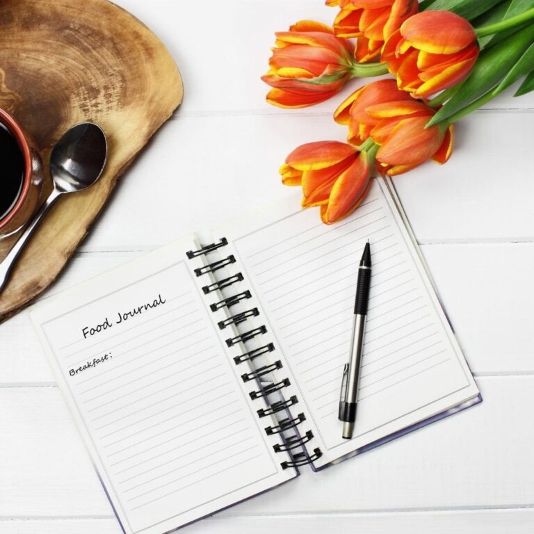 Food Journaling Image with food journal, orange tulips, a pen, and a cup of coffee.