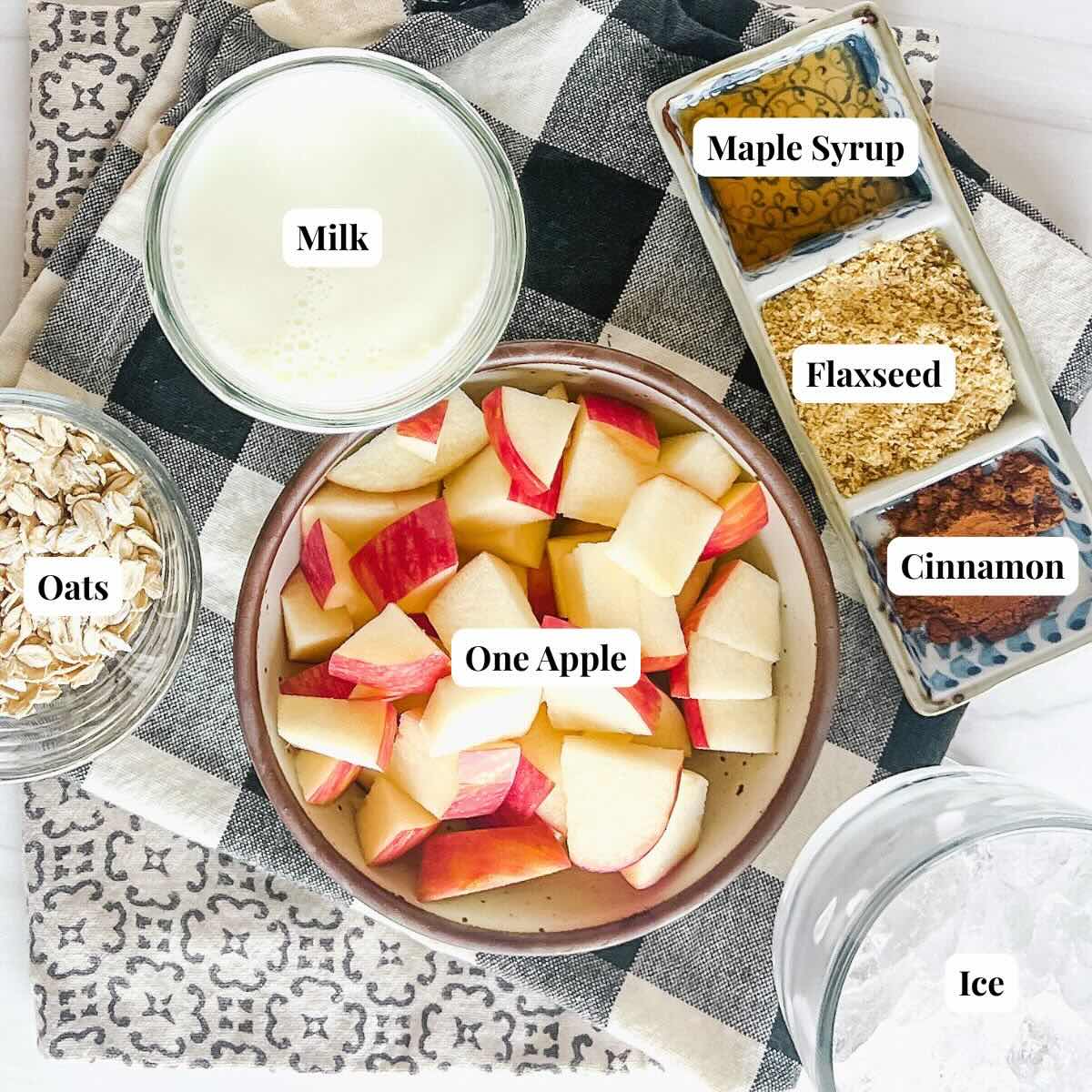 Ingredients to make an apple smoothie: apples, milk, oat, maple syrup, flaxseed, and cinnamon.