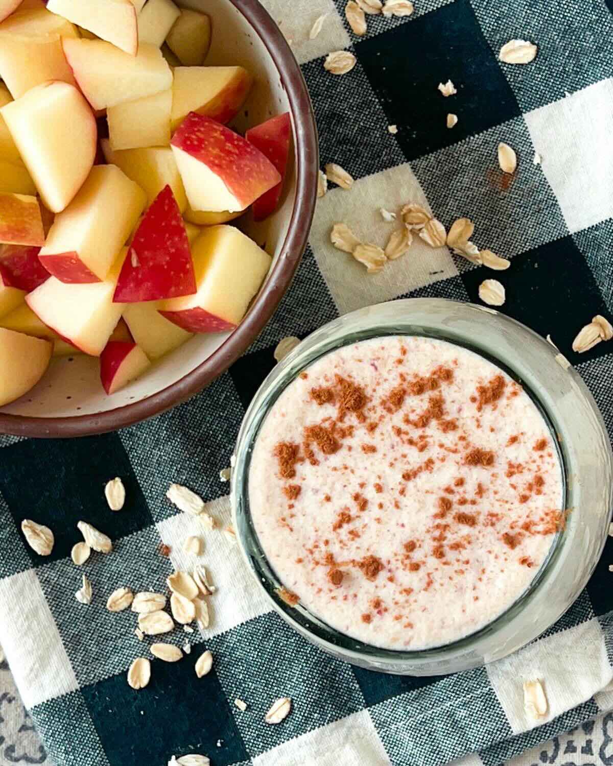 Overhead photo of an apple smoothie and a bowl of apples in the background.