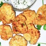 Air Fryer Falafel on a white plate with a bowl of tzatziki sauce.