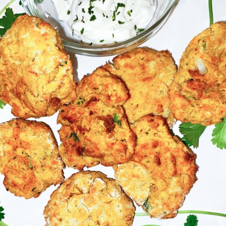 Air Fryer Falafel on a white plate with a bowl of tzatziki sauce.