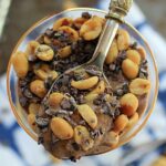 Overhead shot of a chocolate peanut butter breakfast sundae and a spoon.