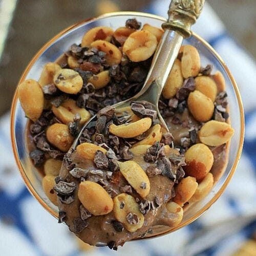 Overhead shot of a chocolate peanut butter breakfast sundae and a spoon.