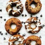 Overhead shot of 6 chocolate chip banana doughnuts on a white marble background.