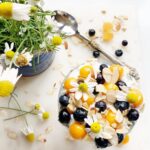 Overhead shot of golden berry chia parfait topped with blueberries, almonds, and chamomile flowers.