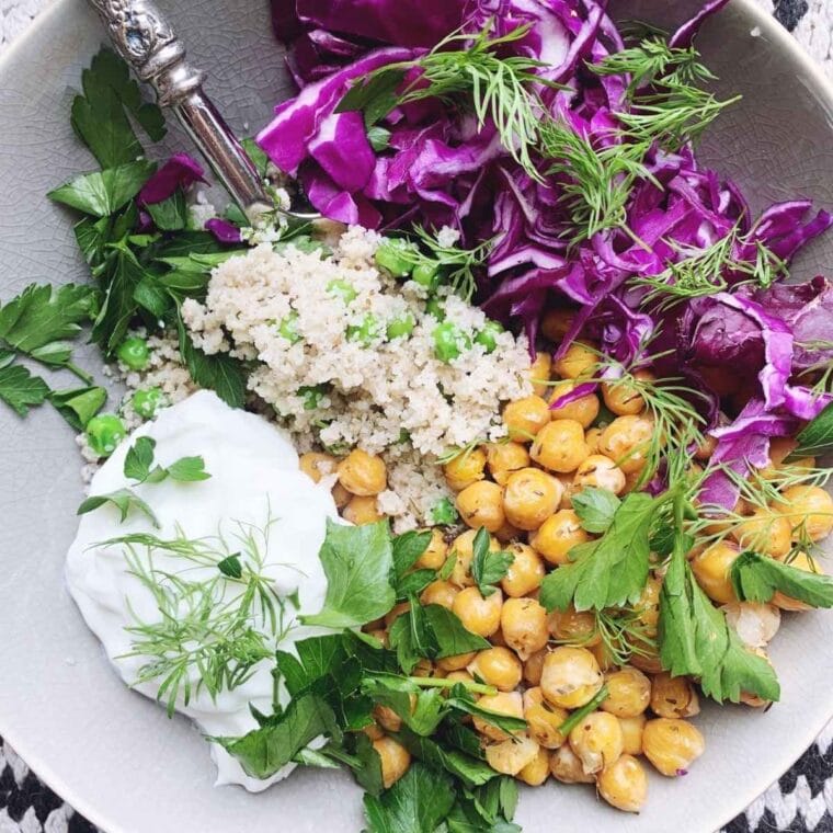 Closeup shot of bowl filled with fonio, chickpeas, cabbage, yogurt, and herbs.