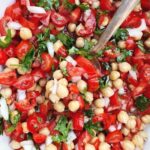Close up photo of chickpea salad with tomatoes, cilantro, and onions.