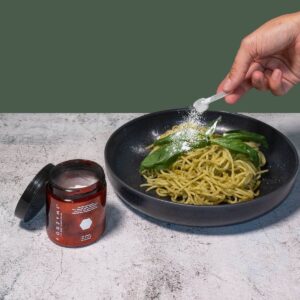 Fodzyme digestive enzyme being sprinkled over a bowl of pasta.