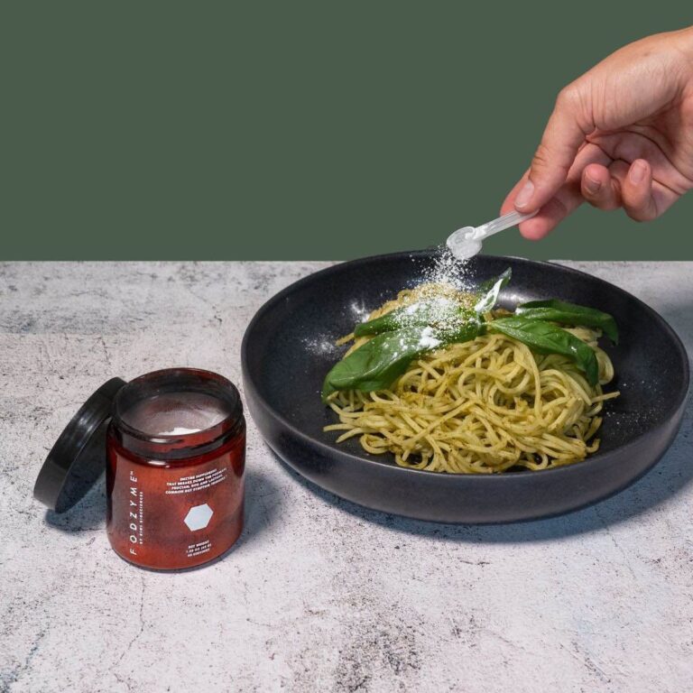 Fodzyme digestive enzyme being sprinkled over a bowl of pasta.