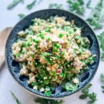 Pottery bowl filled with colorful quinoa arugula salad.