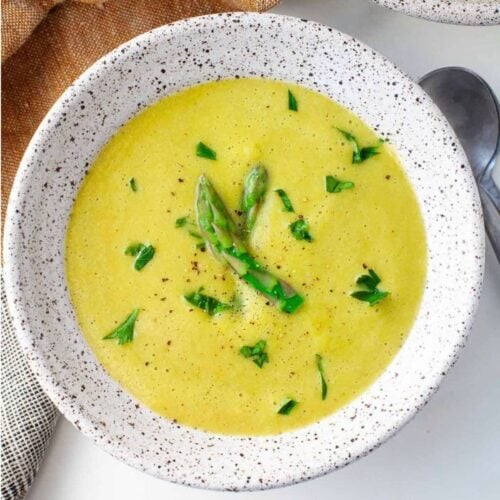 White spotted ceramic bowl with gluten free asparagus soup.