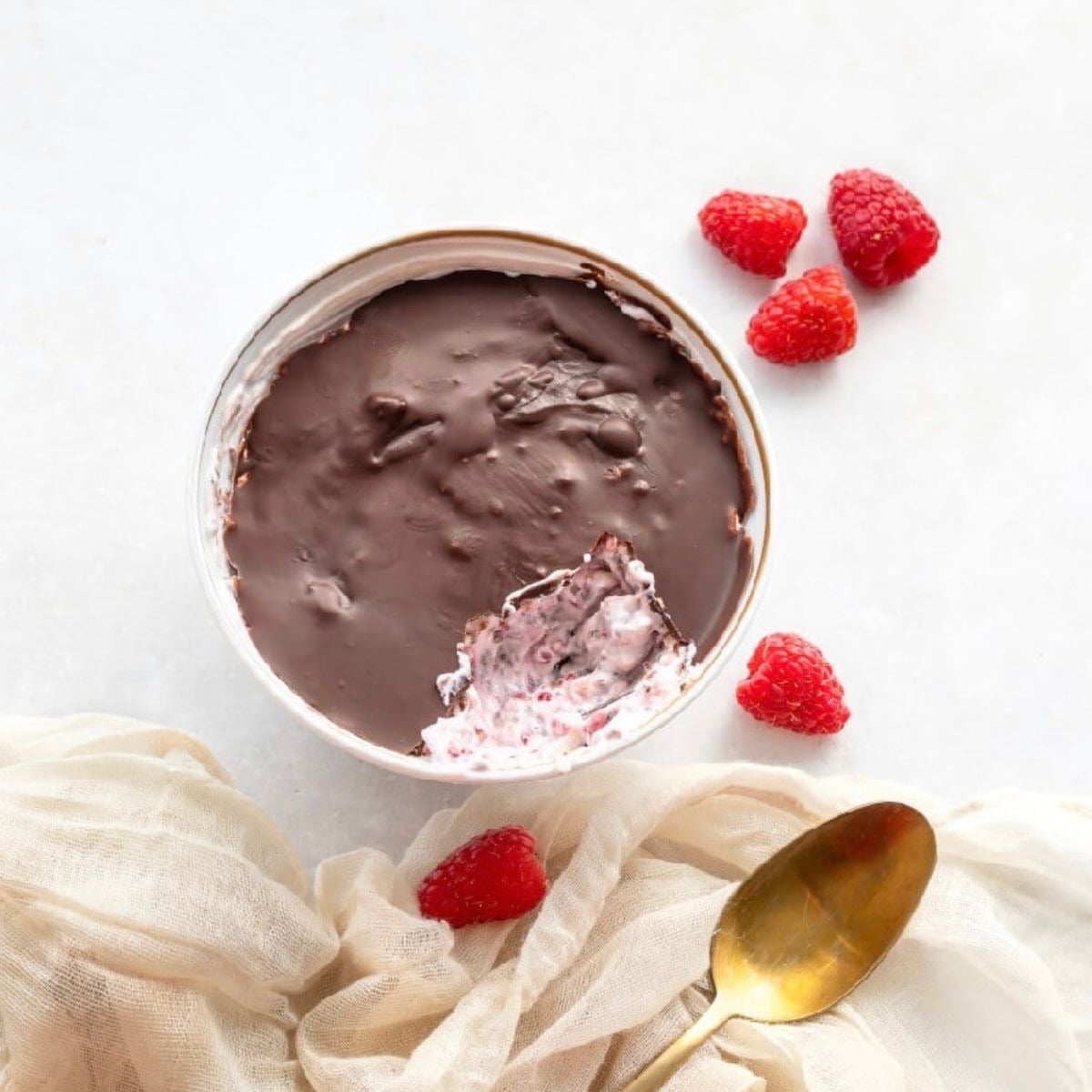 White bowl with raspberry yogurt topped with chocolate.