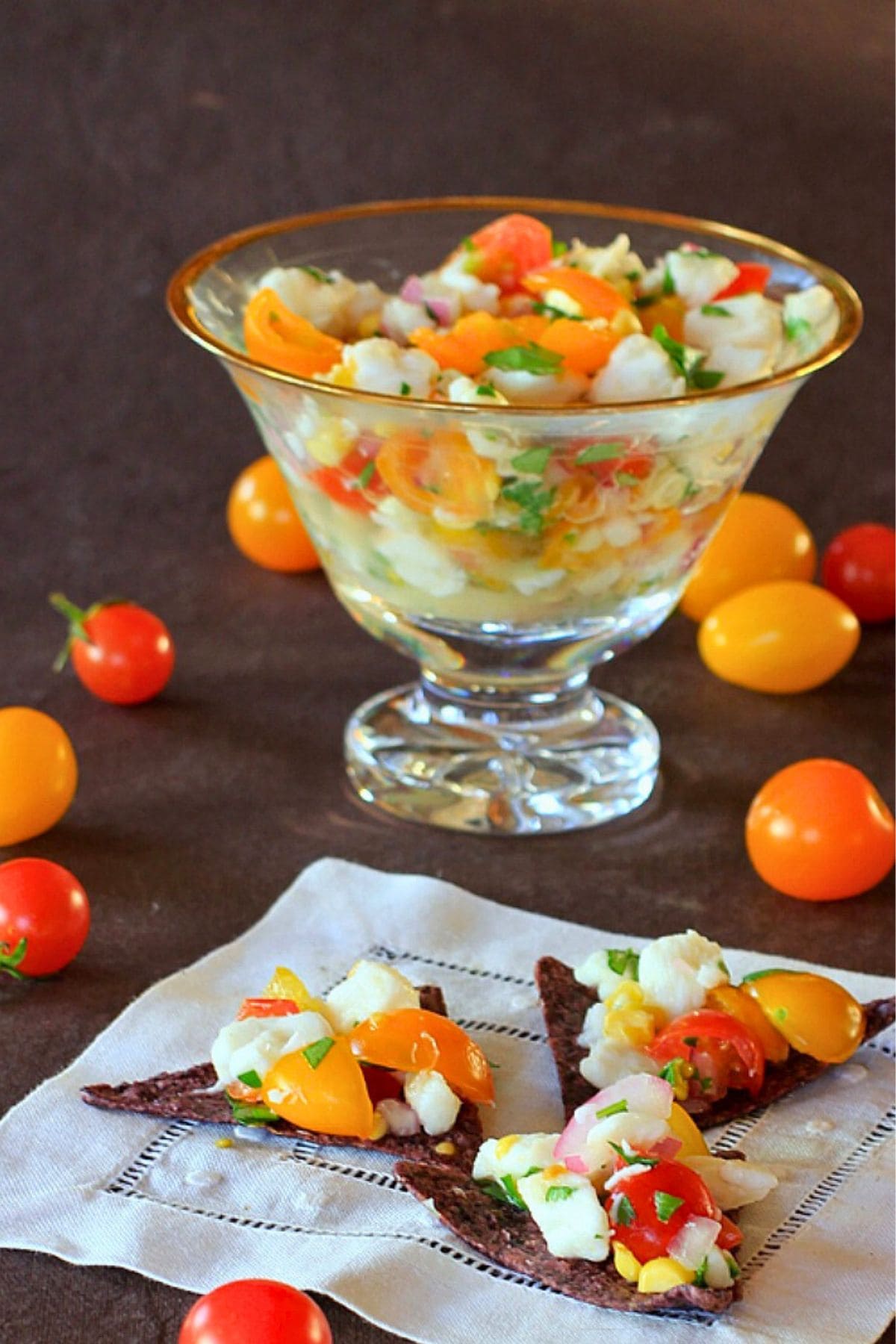 Halibut ceviche on tortilla chips with a bowl of halibut ceviche in the background.