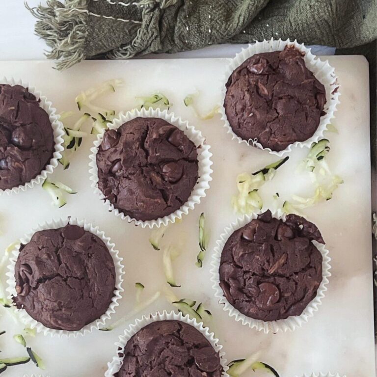 Overhead photo of gluten free zucchini muffins on a white tray with grated zucchini in the background.