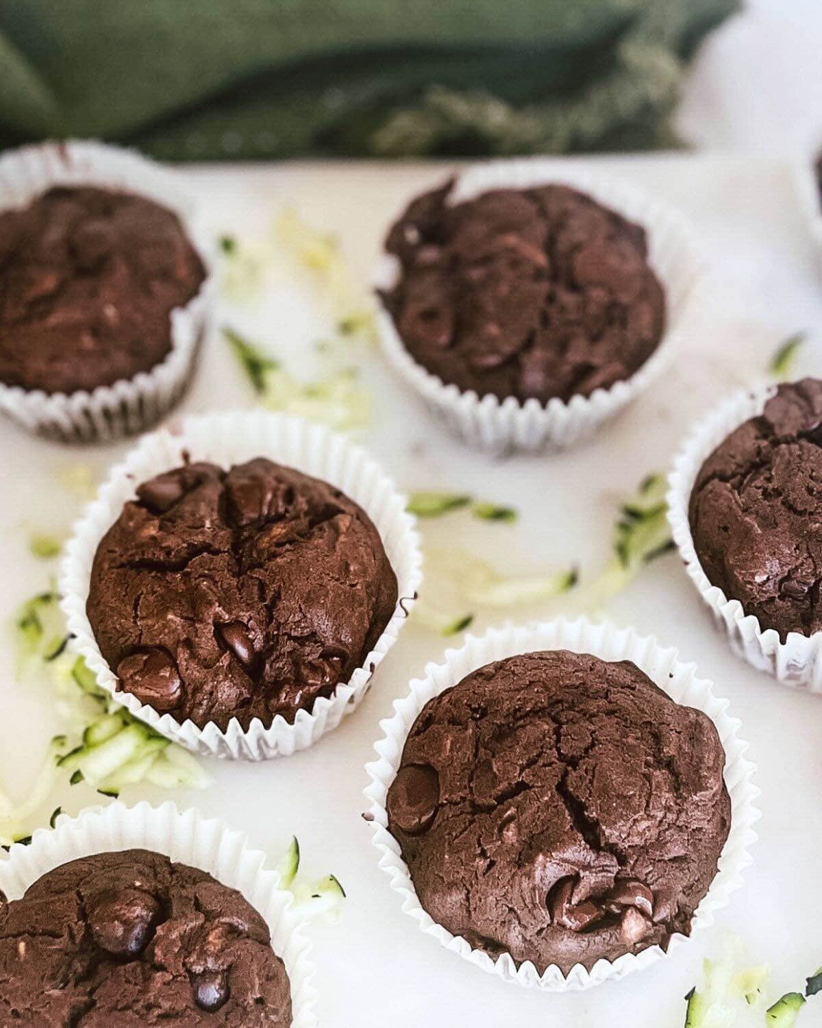 Close up shot of chocolate zucchini muffins with chocolate chips on a white tray.